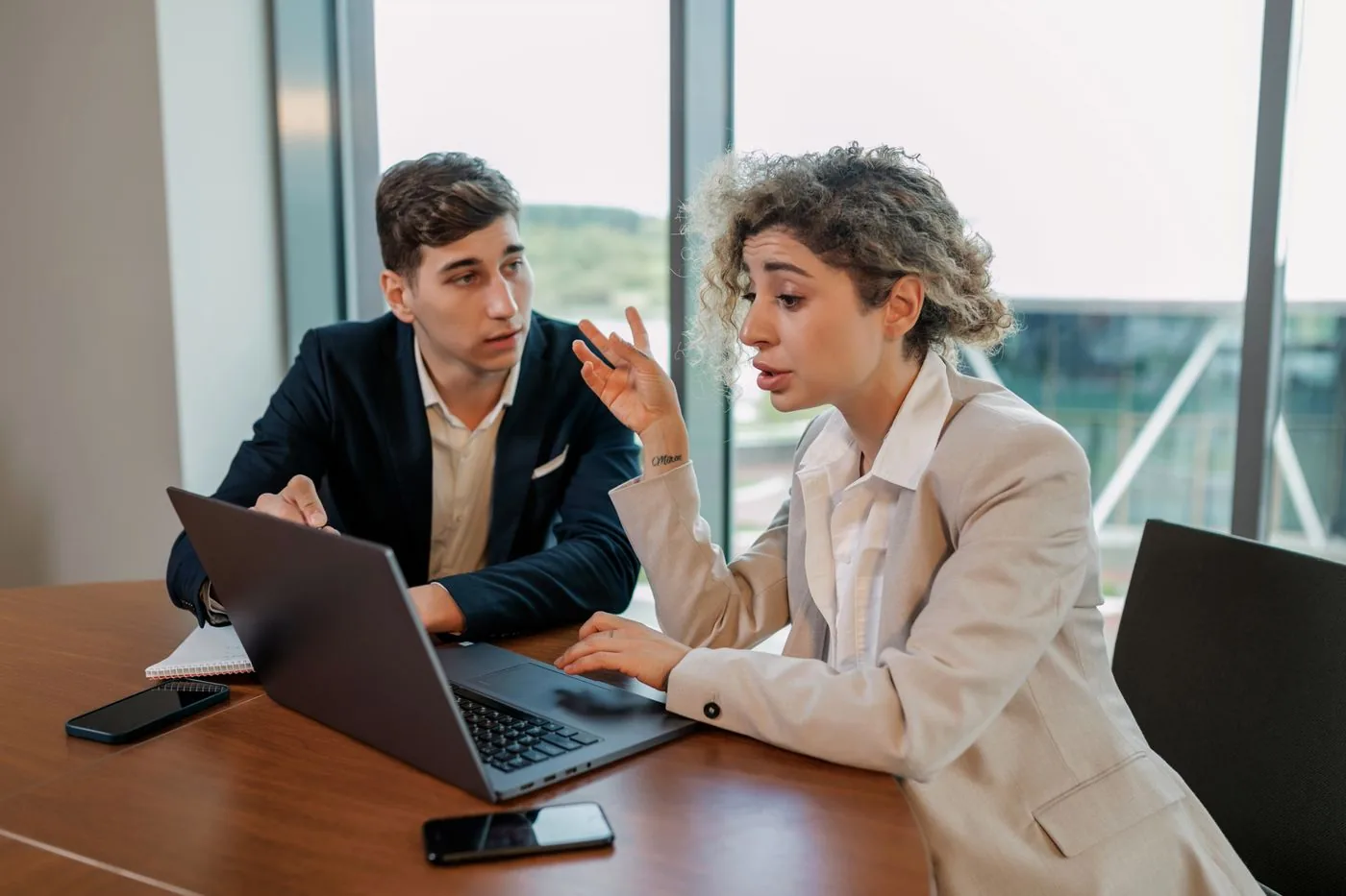 Dos personas platicando sobre un proyecto frente a una laptop